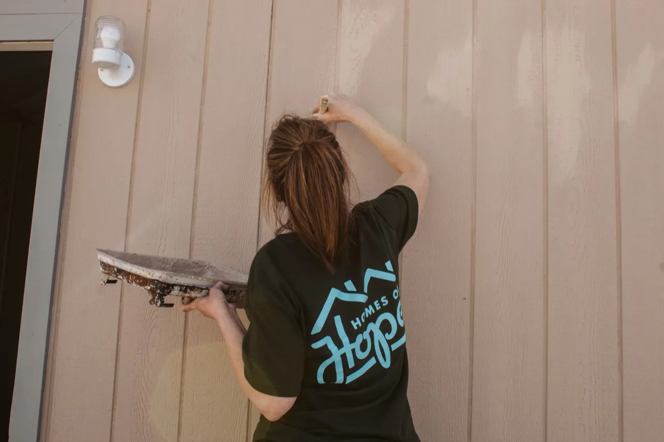 Volunteer smoothing the exterior wall