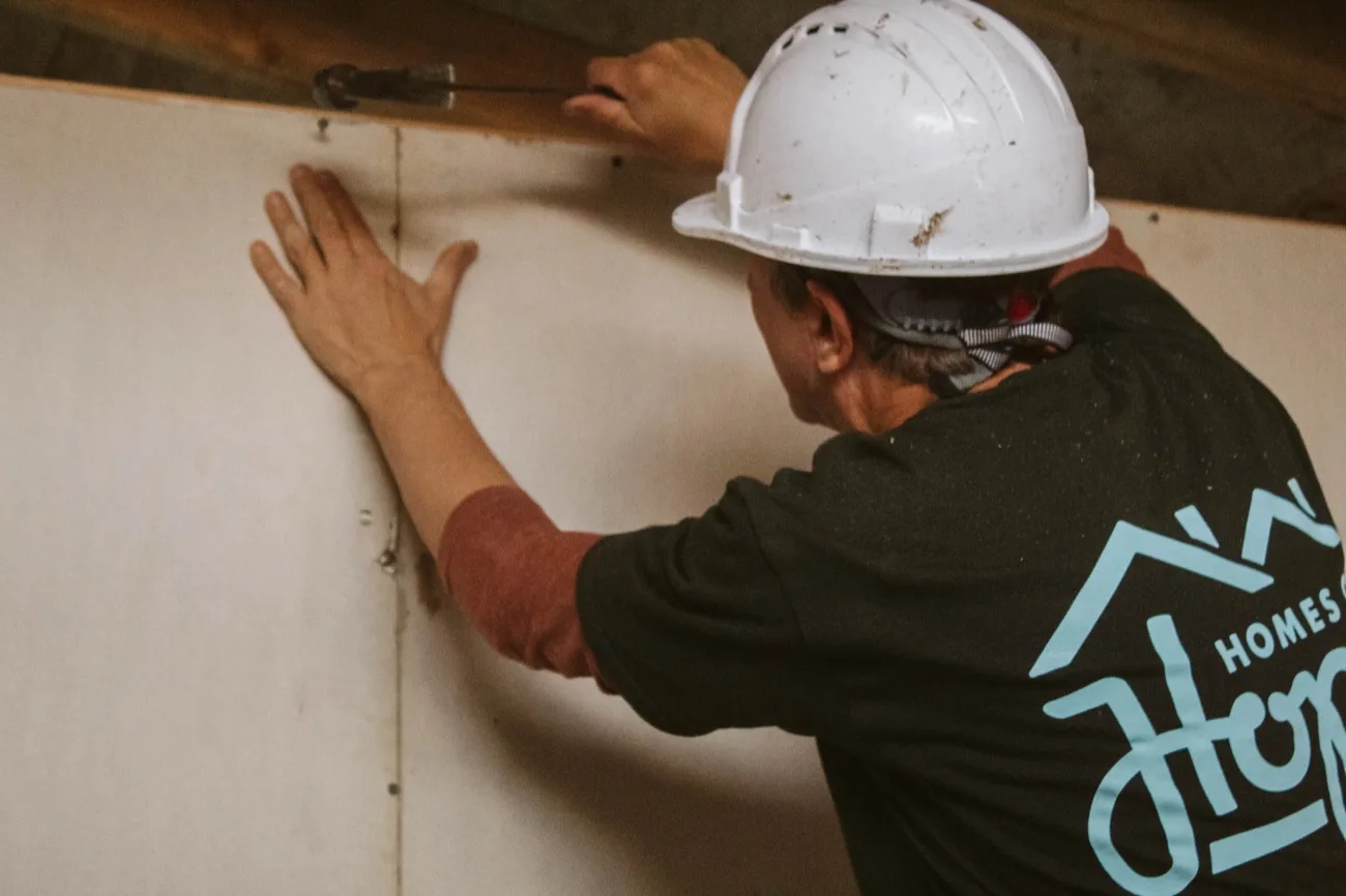 Volunteer fixing panels to the interior wall
