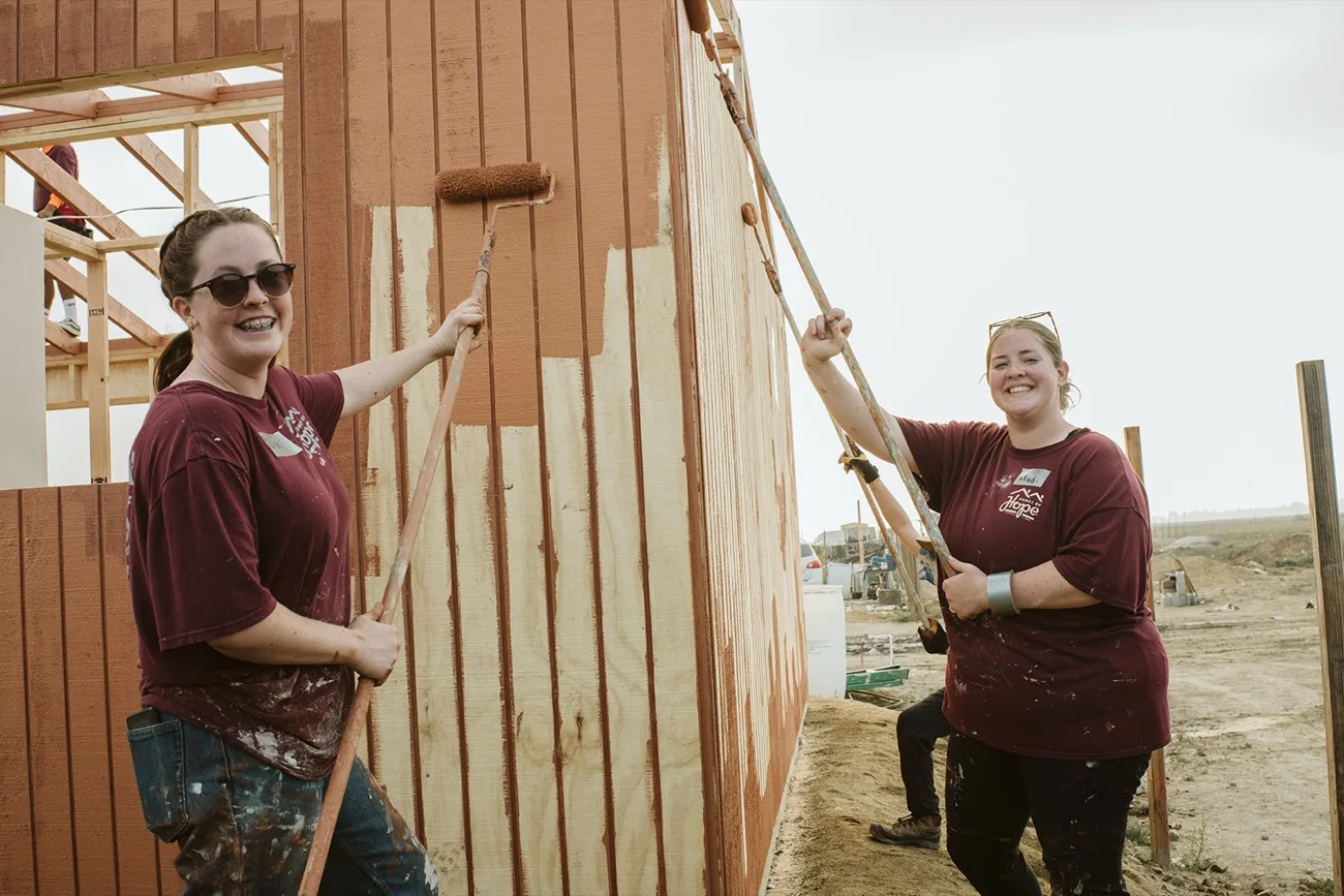 Volunteers painting siding at the build site