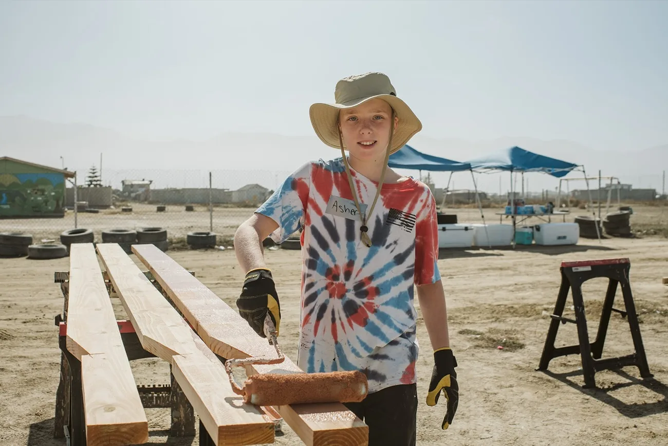 A volunteer staining lumber before the build